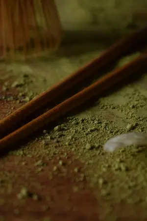 A close view of matcha powder with wooden chopsticks laid across it, fine enough to show the grain.